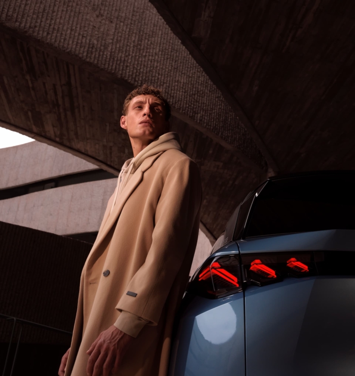 Jeune conducteur à côté d’un SUV Peugeot, choix de financement LLD ou LOA à Valence